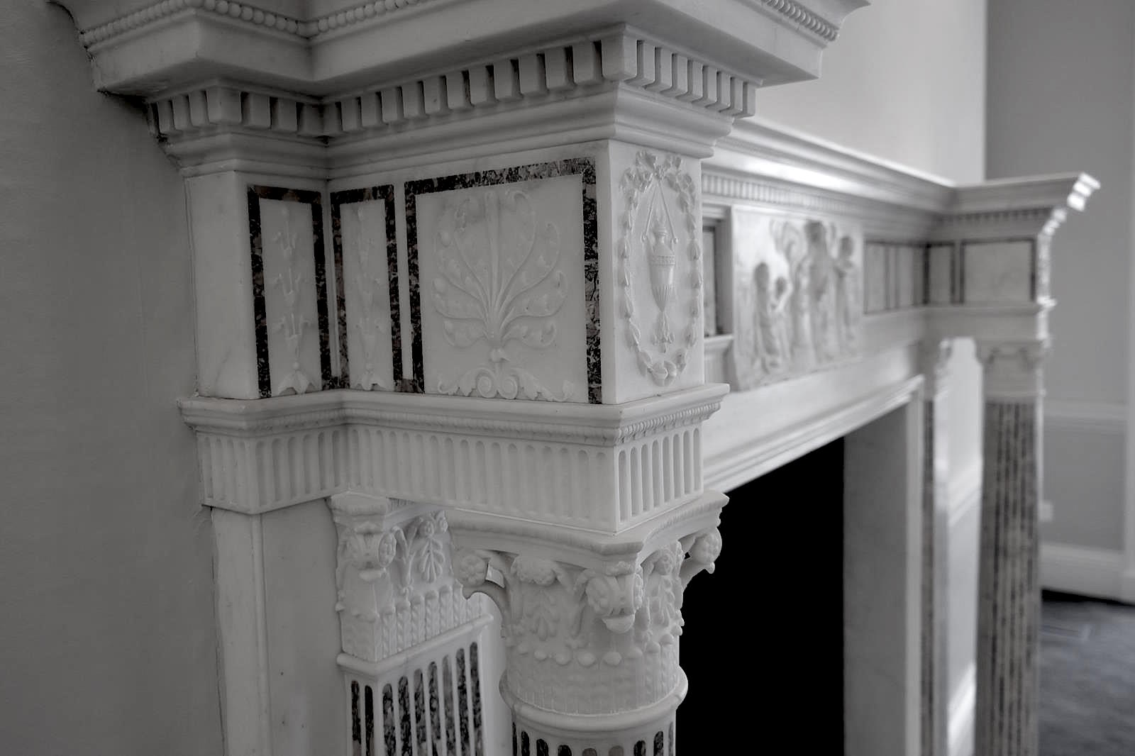 A finely carved white marble chimney-piece / fireplace with a centre-piece tablet depicting a classical, relief in the antique, Roman, manner.