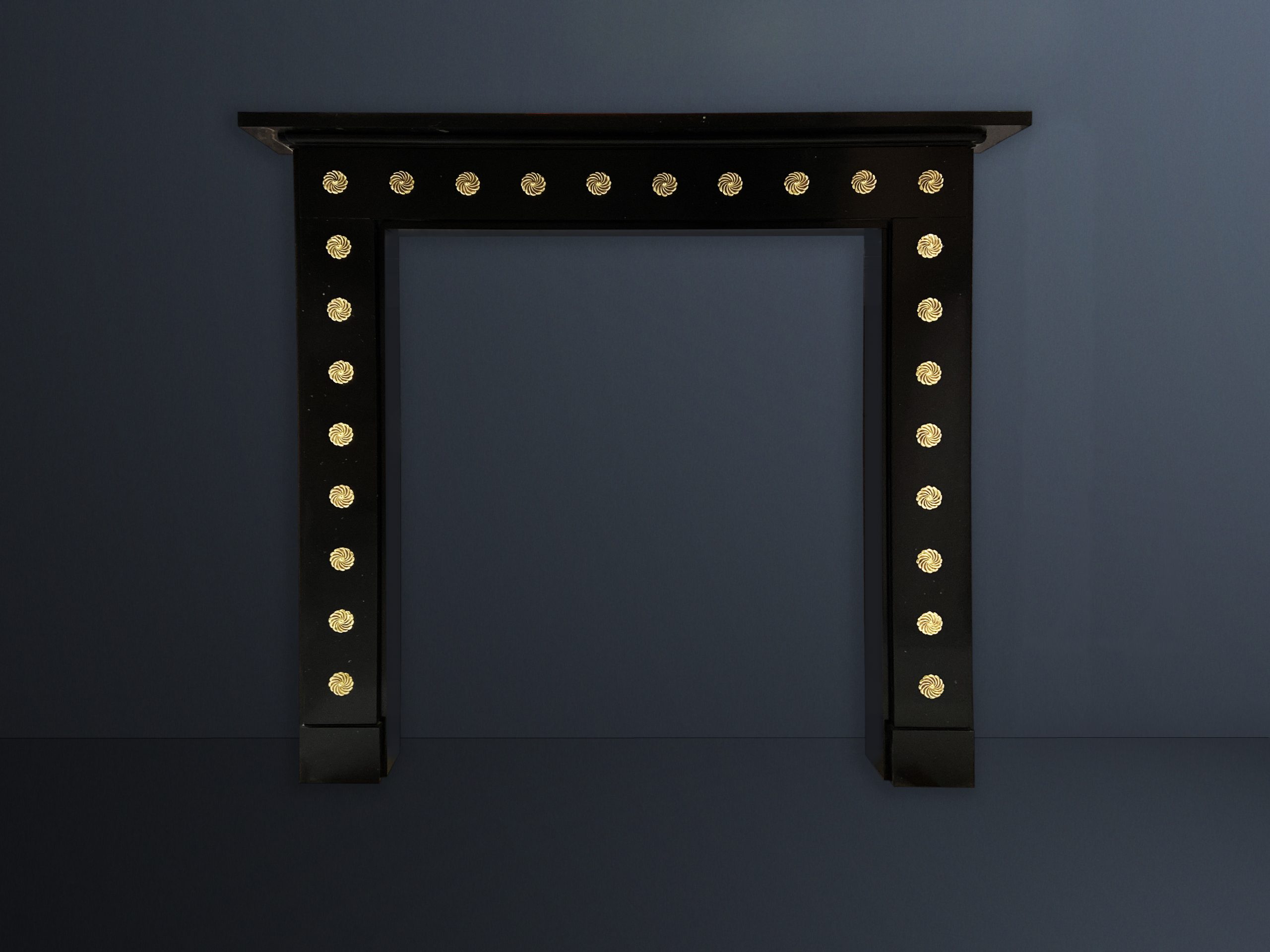A flat black marble chimney-piece / fireplace with gold ormolu mounts on all sides.